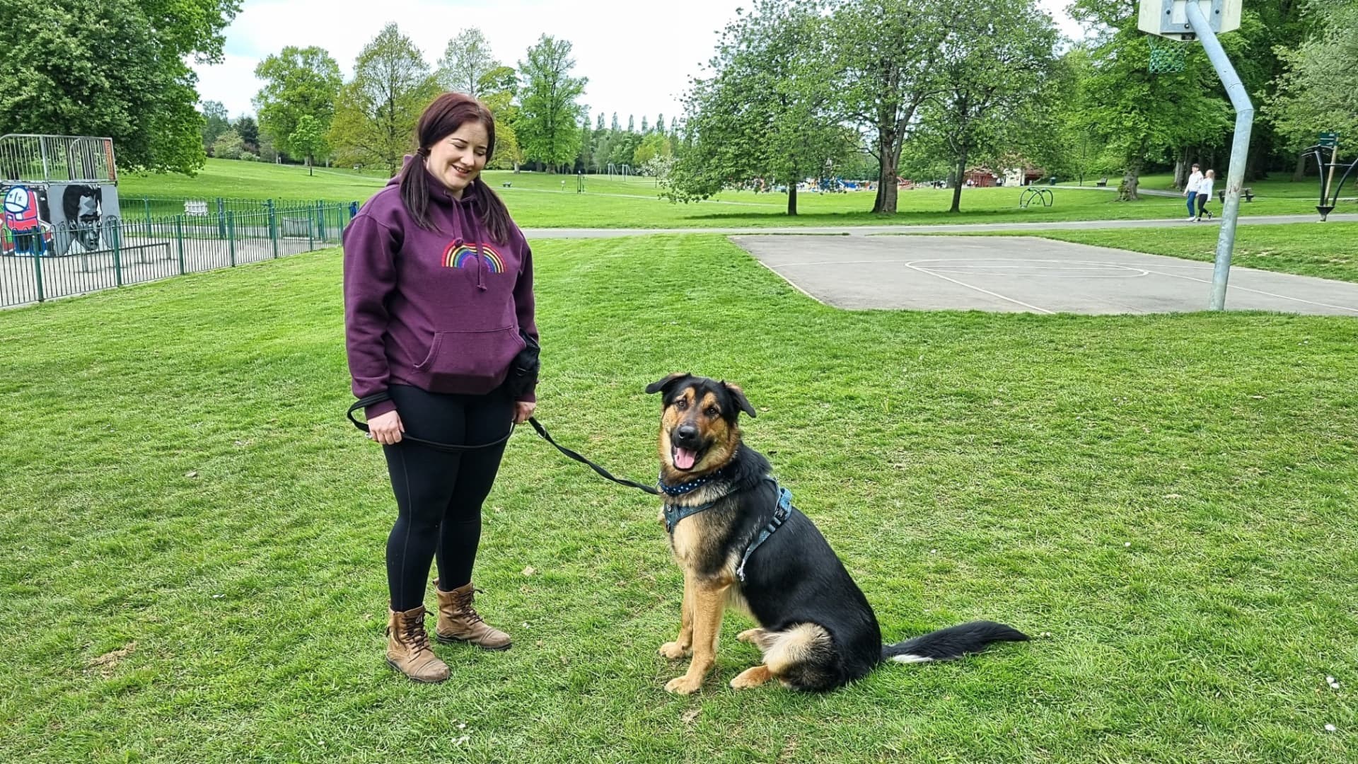 Owner standing calmly with her German shepherd type dog in a sunny Glasgow park