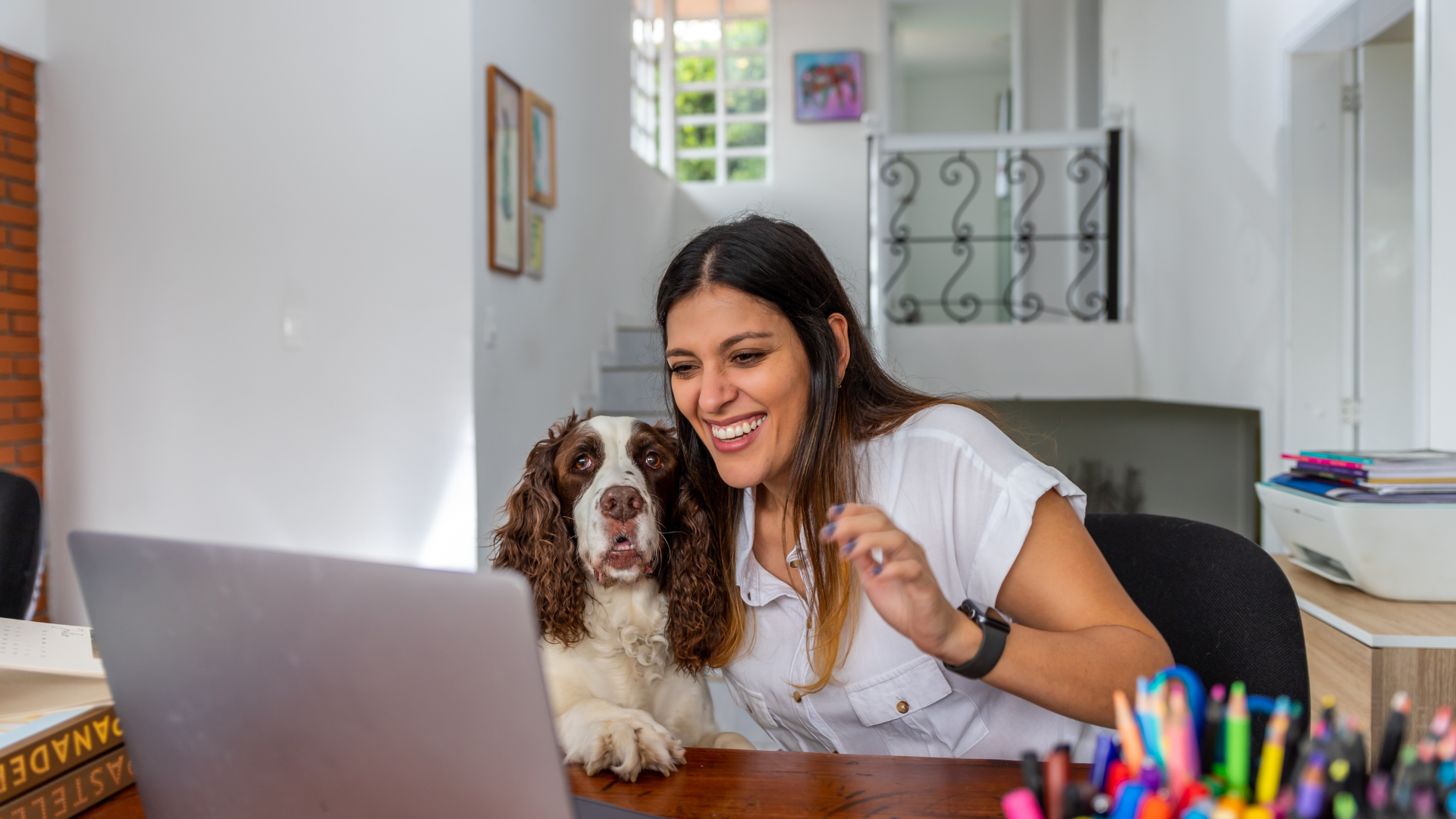 Owner smiling at a laptop with a springer spaniel beside her during a remote one to one dog training video consultation